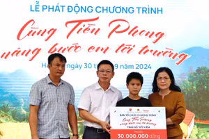 Thứ trưởng Nguyễn Thị Kim Chi và nhà báo Phùng Công Sưởng trao sổ tiết kiệm cho học sinh làng Nủ.