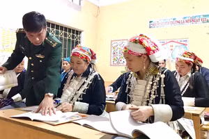 Trung tá Đinh Thái Đạt hướng dẫn học viên tại lớp học xóa mù chữ. 