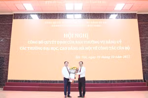 Đồng chí Nguyễn Thanh Sơn - Bí thư Đảng ủy các trường Đại học, Cao đẳng Hà Nội (bên phải) trao quyết định và tặng hoa cho đồng chí Lê Mạnh Hùng.