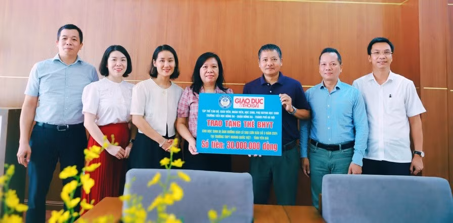 Phó Tổng Biên tập Báo Giáo dục và Thời đại Nguyễn Đức Tuân (thứ 3 từ phải sang) tiếp nhận kinh phí mua thẻ BHYT cho học sinh Trường THPT Hoàng Quốc Việt (TP Yên Bái, tỉnh Yên Bái) từ đại diện tập thể CBGVNV, học sinh và phụ huynh Trường Tiểu học Đống Đa (Hà Nội).