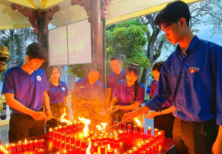 Trọng Văn (bên trái) tham gia thắp nến tri ân tại đền thờ liệt sĩ Thị trấn Mỏ Cày (Bến Tre). Ảnh: NVCC