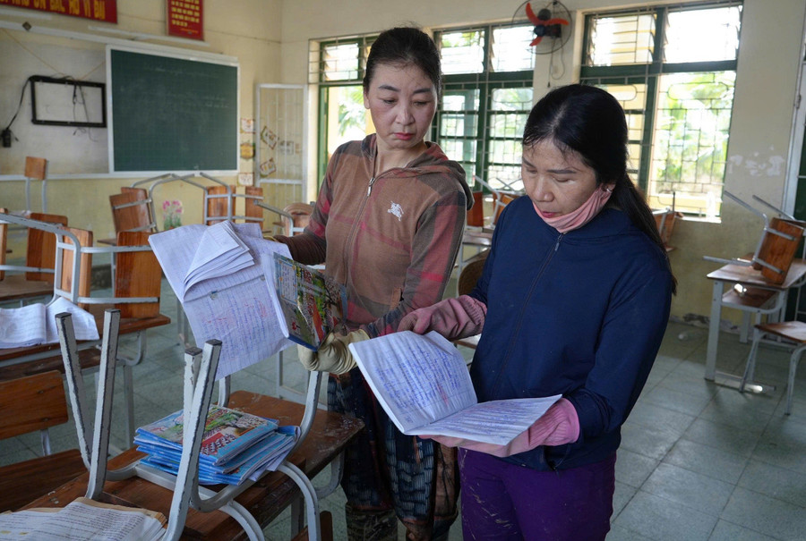 Giáo viên Trường Tiểu học Phạm Hồng Thái (Lam Thành, Nghệ An) kiểm tra lại đồ dùng, sách vở học sinh sau lũ. Ảnh Hồ Lài