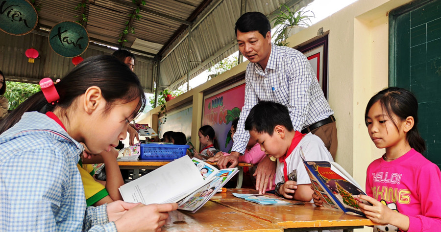 Thầy Đặng Xuân Viên - Hiệu trưởng Trường Tiểu học Thanh Xuân, xã Phú Xuân (huyện Quan Hóa, Thanh Hóa) và học sinh trong giờ đọc sách ở thư viện nhà trường.