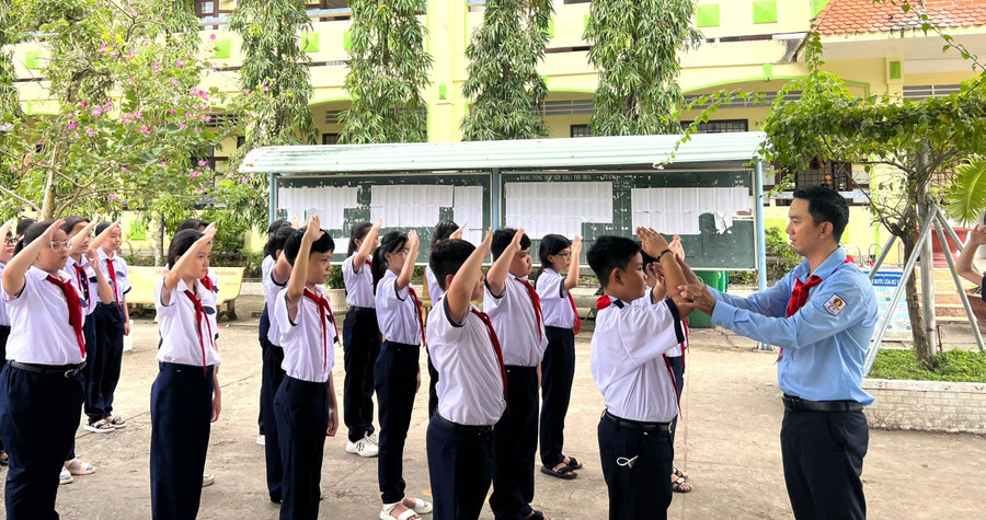 Thầy Nguyễn Chí Tài hướng dẫn học sinh tập nghi thức đội. Ảnh: Quách Mến