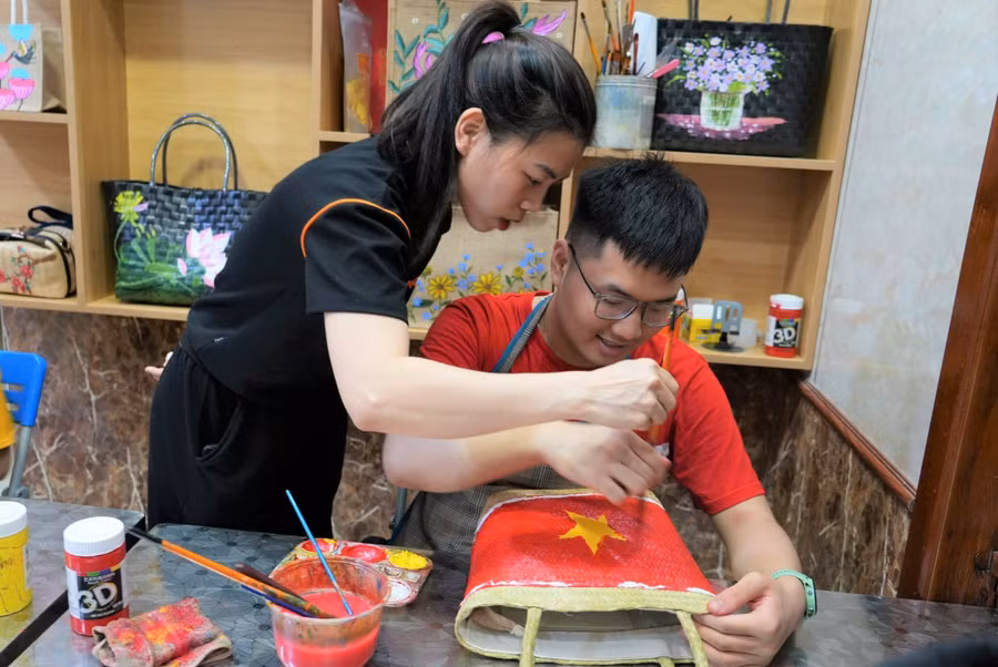 Cô giáo hướng dẫn trẻ vẽ tranh lên túi cói. Ảnh: Hồ Lài 