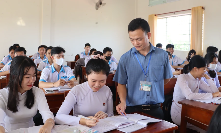 Thầy Hồ Minh Tình hướng dẫn học sinh làm bài. Ảnh: Quách Mến