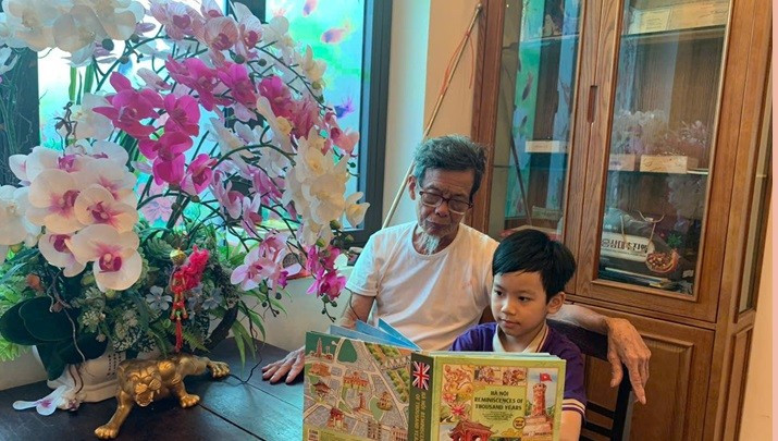 Cụ Nguyễn Hồng Dũng đọc sách cùng Minh Quang. Ảnh: NVCC