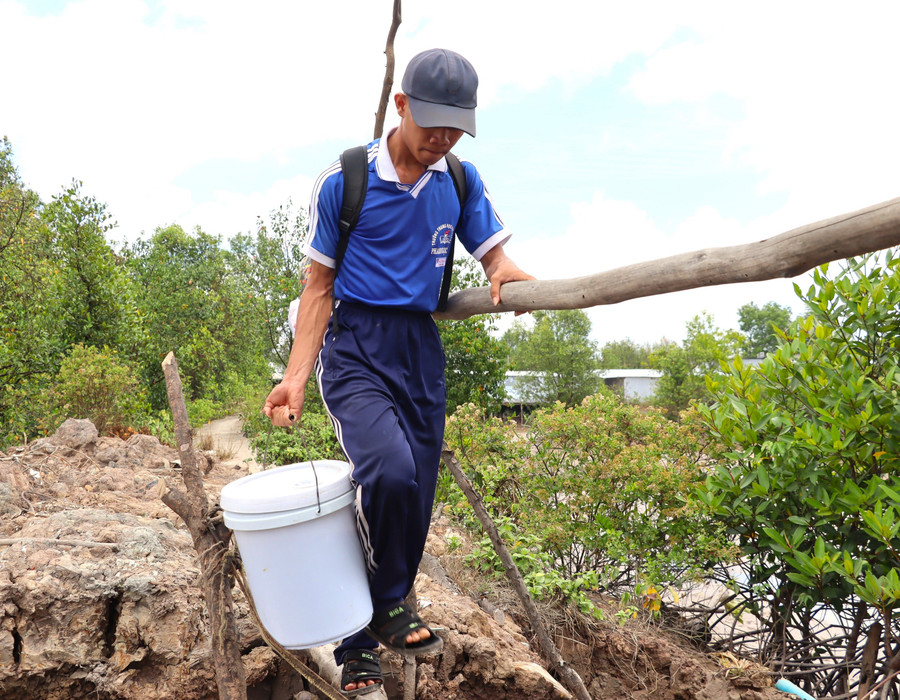 Lê Hữu Do xách từng thùng thức ăn thừa đi qua cầu khỉ. hanh-trinh-chinh-phuc-tri-thuc-cua-nam-sinh-ngheo-1.jpg