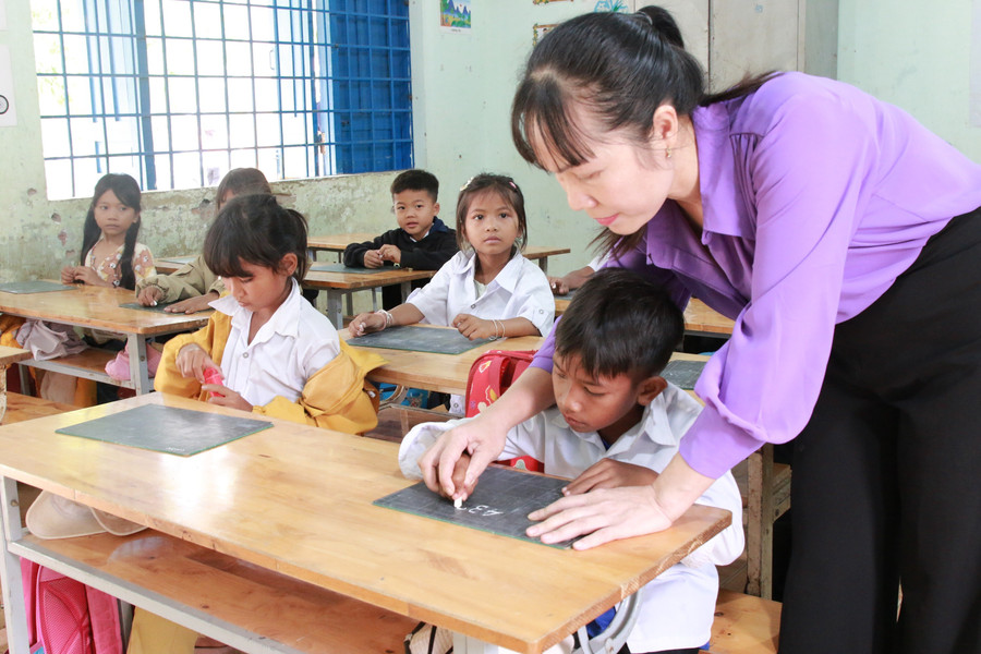 Cô Trần Thị Lệ uốn nắn nét chữ cho học sinh. gieo-mam-uoc-mo-cho-hoc-tro-ngheo-vung-can-cu-cach-mang-4-6530.jpg