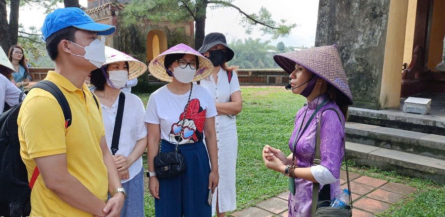 Hướng dẫn viên du lịch hướng dẫn cho khách tham quan tại di tích chùa Thiên Mụ (TP Huế). Ảnh: Quốc Hải 