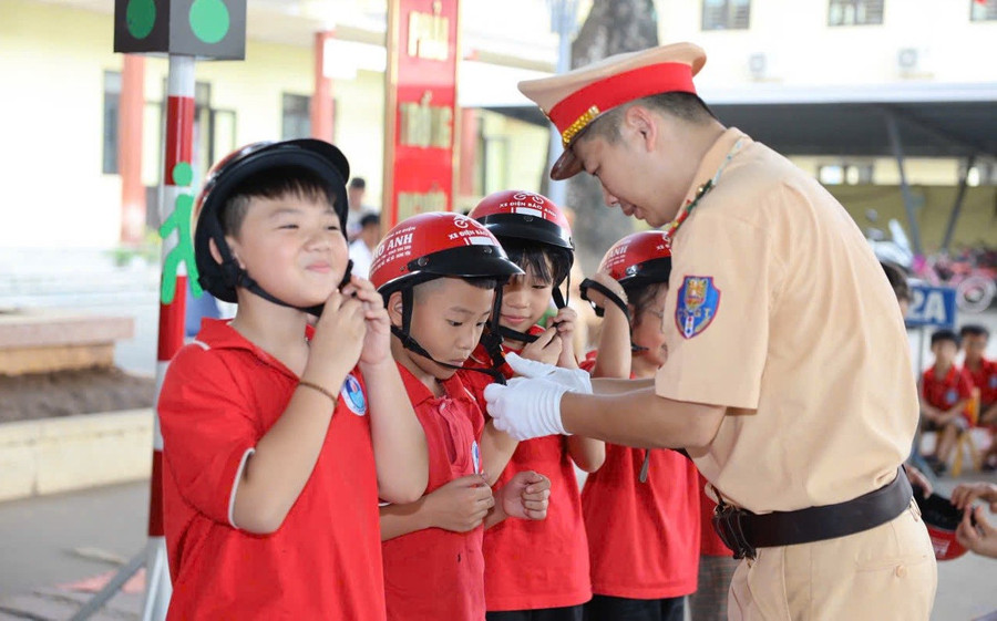 Học sinh được Cảnh sát giao thông hướng dẫn sử dụng mũ bảo hiểm.