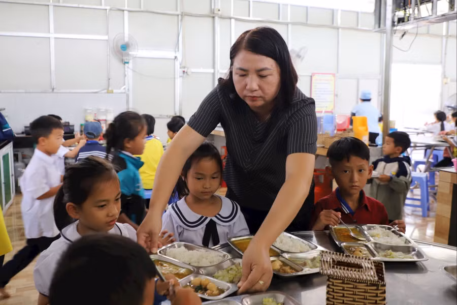Cô Dung lấy cơm cho các em. 