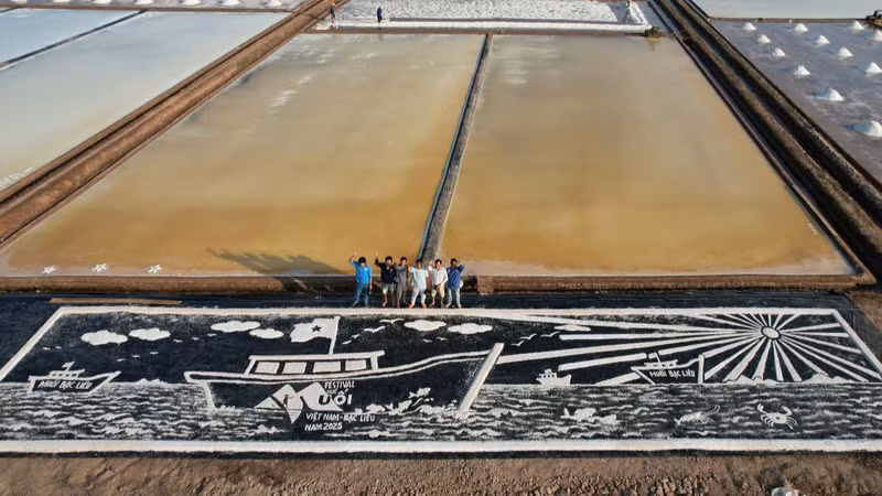 Bức phù điêu mang thông điệp "vươn khơi đón ánh bình minh", dài 25 m, rộng 5m, làm từ khoảng 300 kg muối trắng, tạo hình trên một tấm bạt. (Ảnh: Phan Thanh Cường). tranh-muoi.jpg