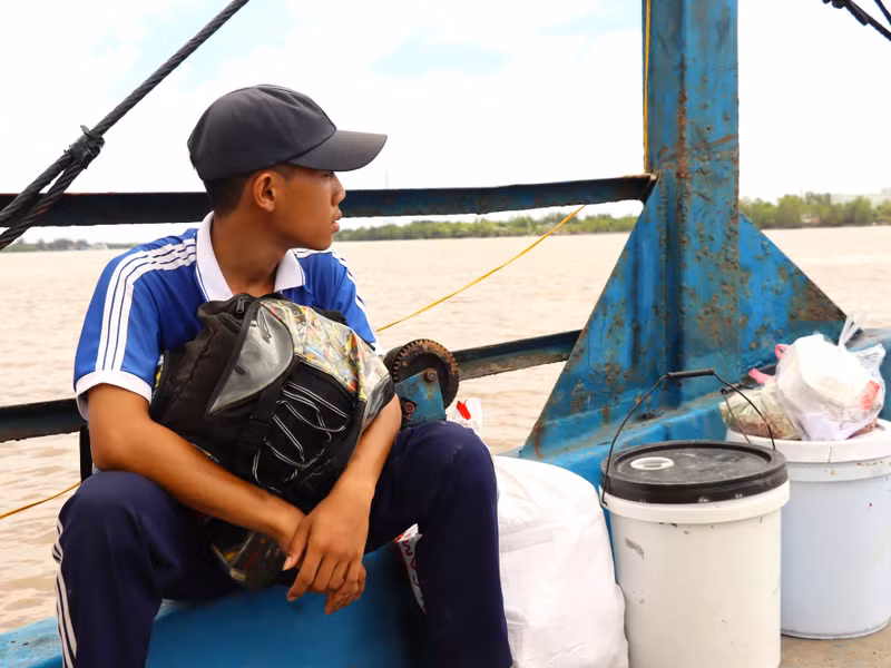 Lê Hữu Do trên phà qua sông cùng 2 thùng đựng thức ăn thừa và bao đựng phế liệu. do-17.jpg