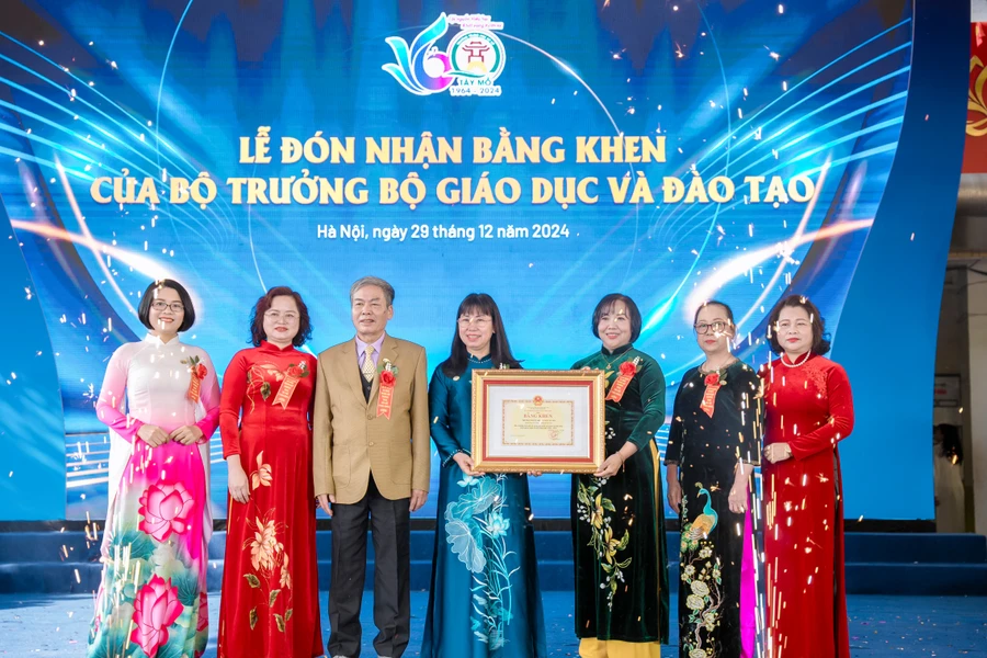 Bà Đỗ Thị Thúy Hà (giữa) - Phó Chủ tịch UBND quận Nam Từ Liêm trao Bằng khen của Bộ trưởng Bộ GD&ĐT cho lãnh đạo Trường THCS Tây Mỗ tại buổi lễ. 