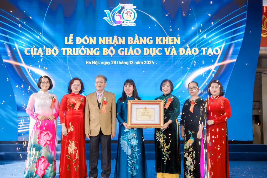 Bà Đỗ Thị Thúy Hà (giữa) - Phó Chủ tịch UBND quận Nam Từ Liêm trao Bằng khen của Bộ trưởng Bộ GD&ĐT cho lãnh đạo Trường THCS Tây Mỗ tại buổi lễ. 