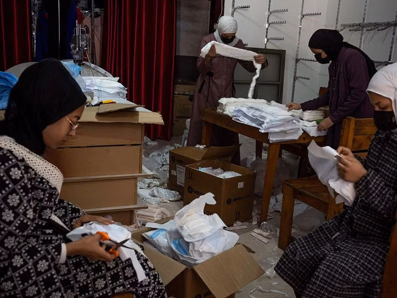 “Nếu các ngân hàng mở cửa, bạn sẽ cần vay tiền để mua bỉm,” ông nói khi trong xưởng có nhiều người đang sử dụng máy may để sản xuất tã bỉm. Chùm ảnh thợ may Gaza thời chiến