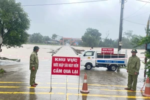 Lực lượng chức năng cắm biển cảnh báo, canh gác không để người và các phương tiện qua lại cầu tràn Phố Giang, thị trấn Phố Châu, huyện Hương Sơn. (Ảnh: A.D)