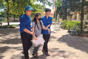 Thí sinh Nguyễn Thị Thanh Nhàn được các tình nguyện viên hỗ trợ dìu vào phòng thi. (Ảnh: T.H)