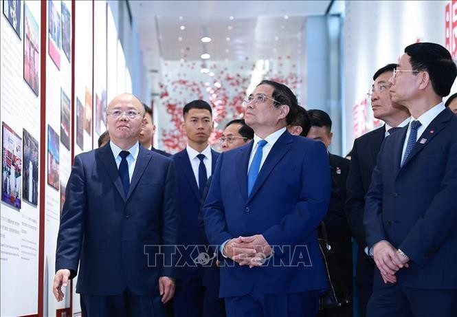 Thủ tướng Phạm Minh Chính nghe giới thiệu về quá trình phát triển của Sàn giao dịch chứng khoán Thượng Hải. Ảnh: Dương Giang/TTXVN