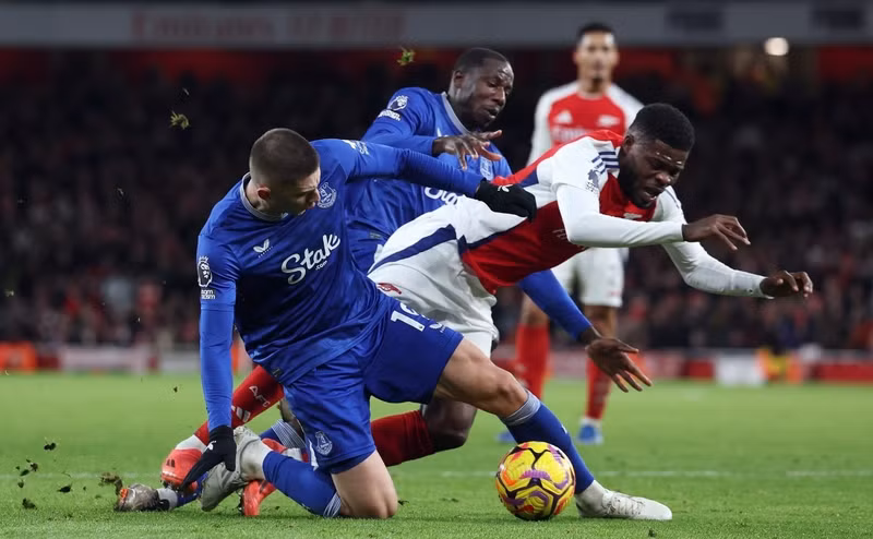 Thomas Partey (áo đỏ) bị đốn ngã bởi một pha vào bóng vụng về của Vitaly Mykolenko. r-action-english-premier-league.jpg