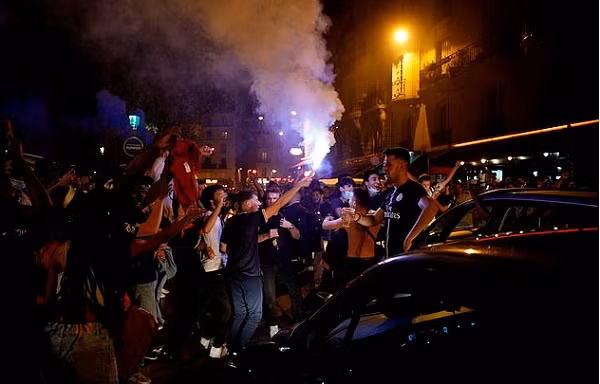 Đám đông tụ tập hò hét đốt pháo sáng và pháo hoa.