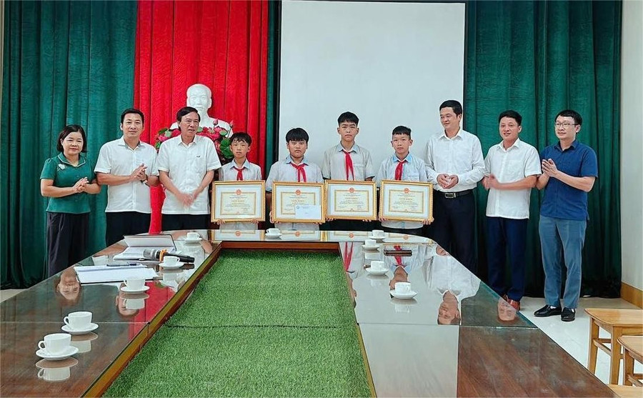 Lãnh đạo UBND xã Tu Vũ tặng giấy khen cho 4 học sinh.