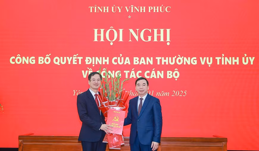 Phó Bí thư Thường trực Tỉnh ủy Vĩnh Phúc Bùi Huy Vĩnh (phải) trao Quyết định và tặng hoa chúc mừng ông Lại Hữu Tuyển.