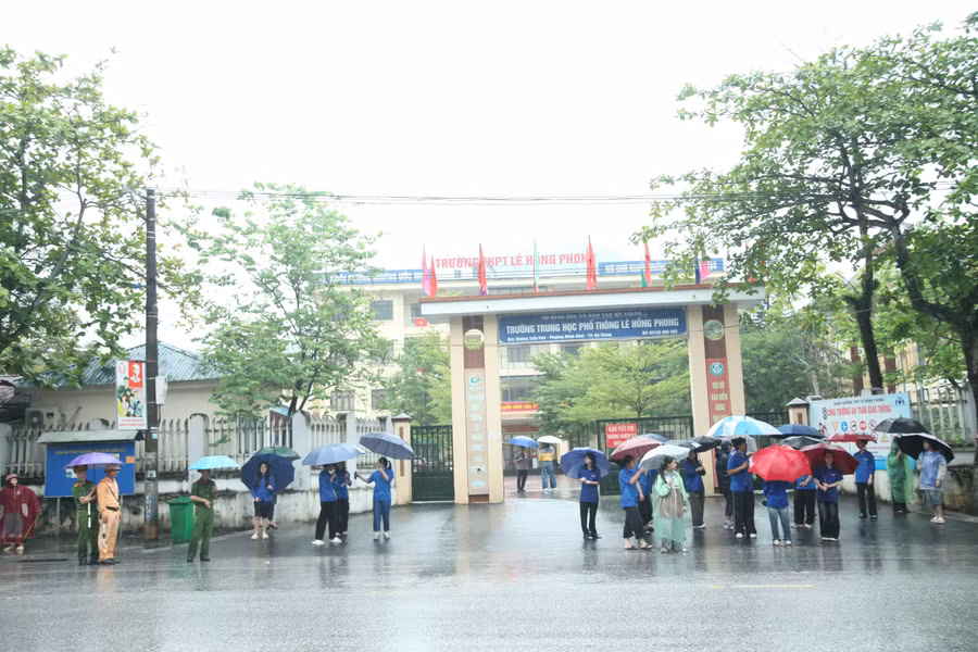 Các thí sinh đội mưa đến tham dự khi thi tại điểm thi Trường THPT Lê Hồng Phong, TP Hà Giang.