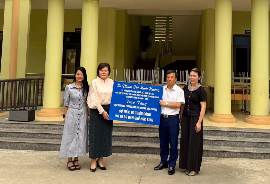 Bà Phạm Thị Minh Hường (thứ 2 từ trái qua) trao tặng tiền và bàn ghế cho nhà trường.