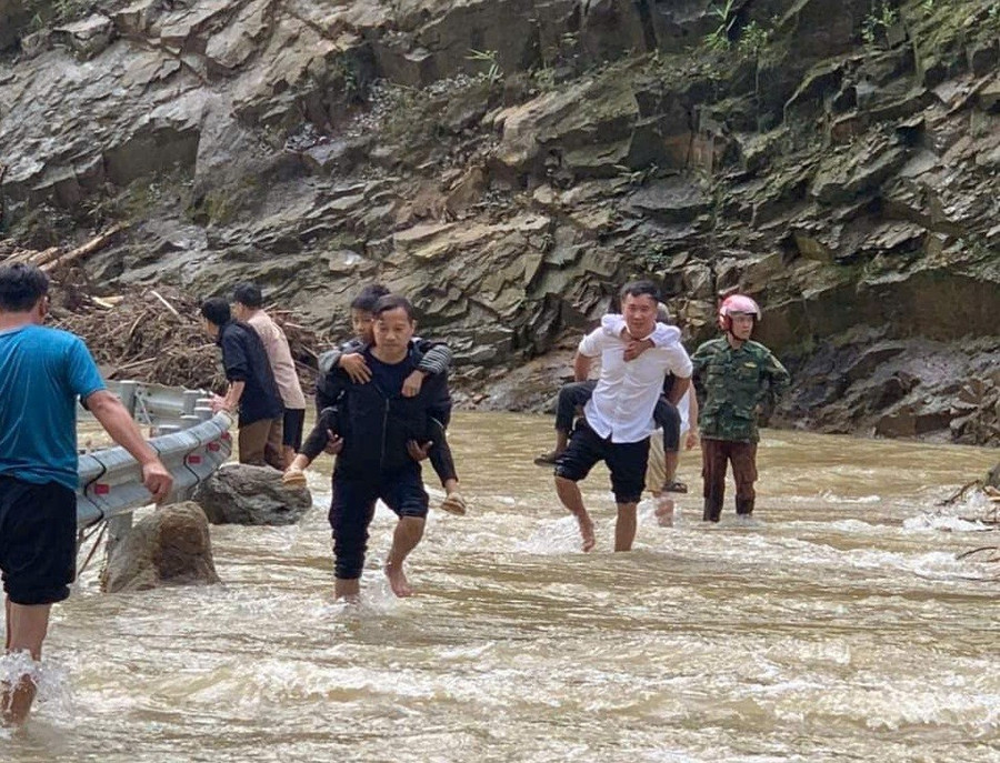 Thầy Nguyễn Chí Anh (áo sáng) cõng từng em học sinh qua dòng nước lũ ngập sâu để đón các em về trường an toàn sau bão số 3.