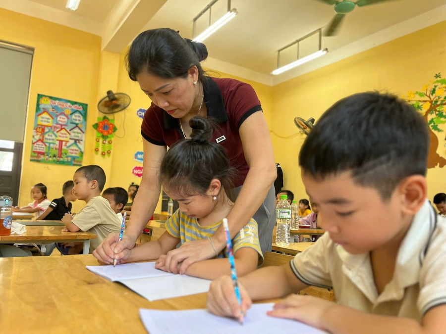 Giáo viên Trường tiểu học Minh Quang, xã Bình Xa hướng dẫn học sinh cách cầm bút. 1000039775.jpg