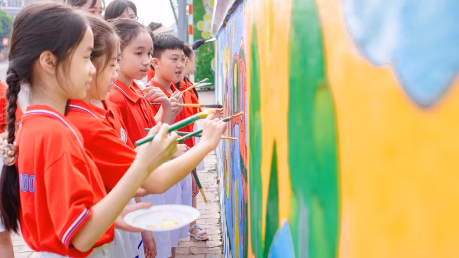 Các em học sinh Trường Tiểu học Lê Văn Tám thể hiện bức tranh tường của mình.
