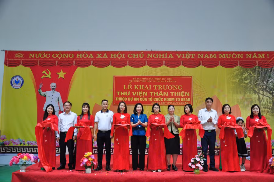 Các đại biểu cùng cán bộ giáo viên học sinh nhà trường cắt băng khai trương thư viện.