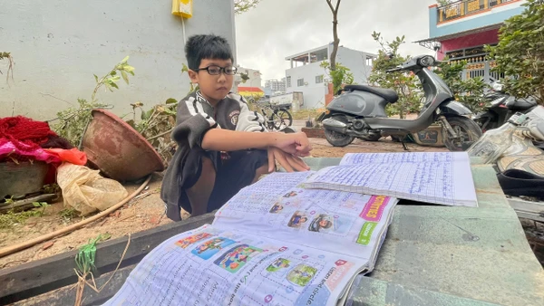 Ngô Tấn Phú - học sinh lớp 5B, Trường Tiểu học số 1 Nhơn Bình (phường Quy Nhơn Đông, tỉnh Gia Lai) phơi những cuốn vở ướt sũng nước. Ảnh: Dung Nguyễn