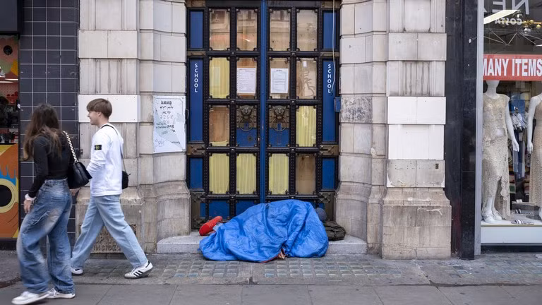 Người vô gia cư ngủ dưới một ô cửa trong một chiếc túi ngủ ở London.