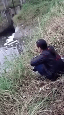 Người phụ nữ thẫn thờ ngồi nhìn chiếc xe chìm nghỉm dưới mương nước. Ảnh cắt từ clip