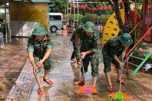 Bộ đội tham gia quét dọn vệ sinh khuôn viên trường học.