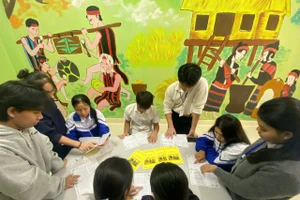 Các bạn học sinh đang học chữ Brũ- Vân Kiều thông qua sổ tay học tập ngoài giờ học.