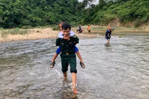 Cán bộ chiến sĩ Đồn Biên phòng Hướng Lập cõng các em vượt suối đến trường khai giảng.