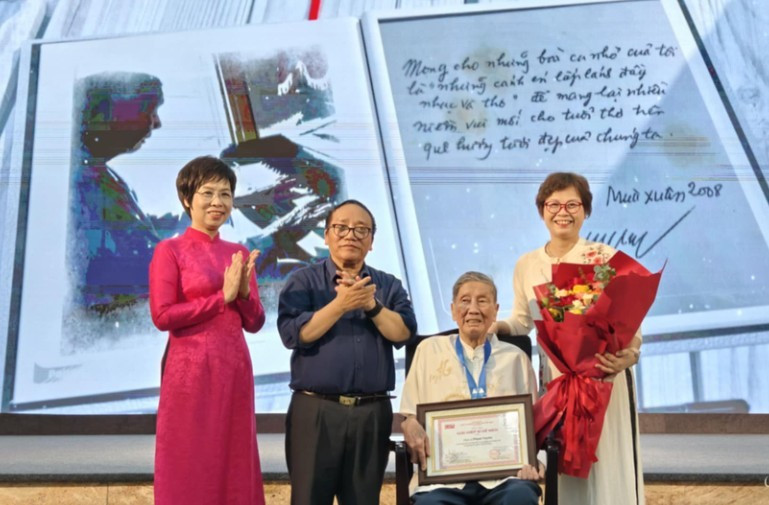 Nhà báo Vũ Việt Trang, Tổng giám đốc TTXVN và nhà thơ Trần Đăng Khoa, Phó Chủ tịch Hội Nhà văn Việt Nam, Chủ tịch Hội đồng giám khảo trao Giải Hiệp sĩ Dế Mèn cho nhạc sĩ Phạm Tuyên. Ảnh: Huy Thông.