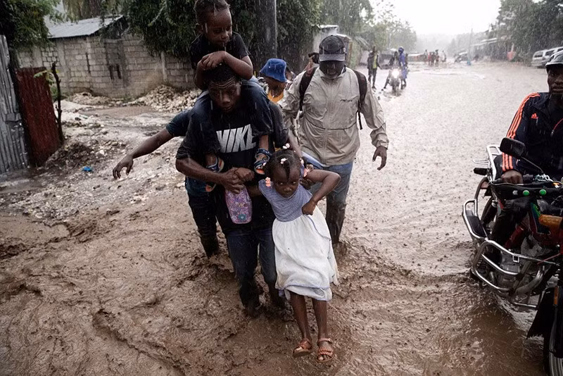 Người dân đi qua đường ngập lụt tại Petit-Goâve, Haiti ngày 30/10. chum-anh-noi-bat-trong-tuan-021105-05.jpg