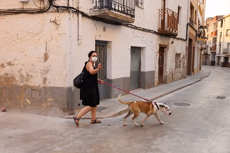 Một phụ nữ đeo khẩu trang để tránh khói khi đi bộ cùng chó ở Xerta – một trong những làng bị phong tỏa do cháy rừng tại tỉnh Tarragona, Tây Ban Nha, ngày 8/7. chum-anh-chay-rung-bung-phat-o-chau-au-0705-018.jpg