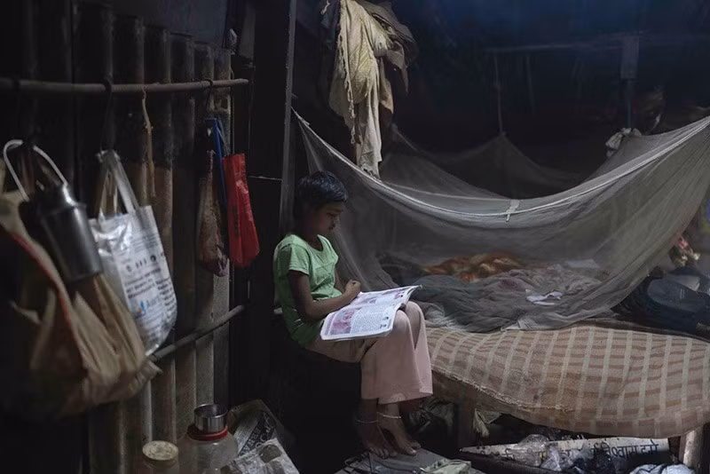 Neelam Krishan, 11 tuổi, học tại nhà ở Thane gần Mumbai, Ấn Độ. Ảnh: AP. Vào buổi tối, học sinh như Krishan sẽ trở về nhà ở vùng ngoại ô của thành phố, nhiều ngôi nhà được dựng tạm từ những tấm tôn, ván ép và bạt che. chum-anh-ngoi-truong-duoi-duong-cao-toc-o-an-do-01.jpg