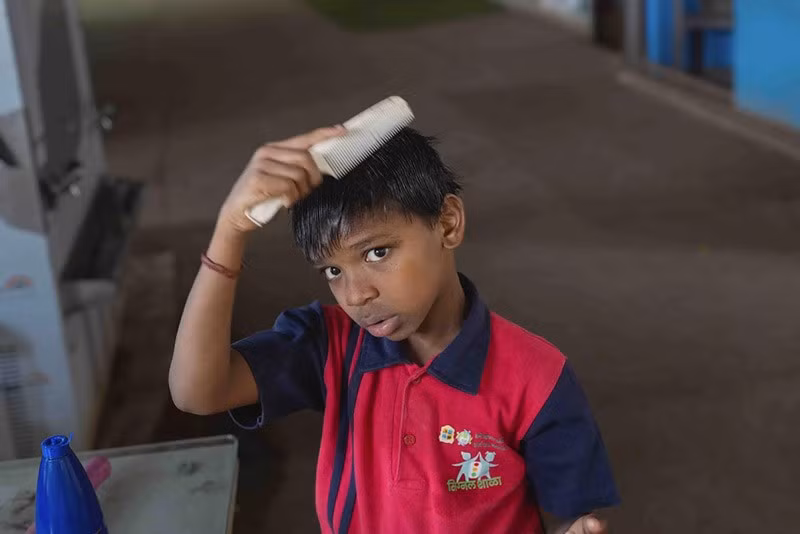 Yash Ganesh Gayakwad, 9 tuổi, chải tóc sau khi tắm tại trường Signal Shala ở Thane. chum-anh-ngoi-truong-duoi-duong-cao-toc-o-an-do-014.jpg