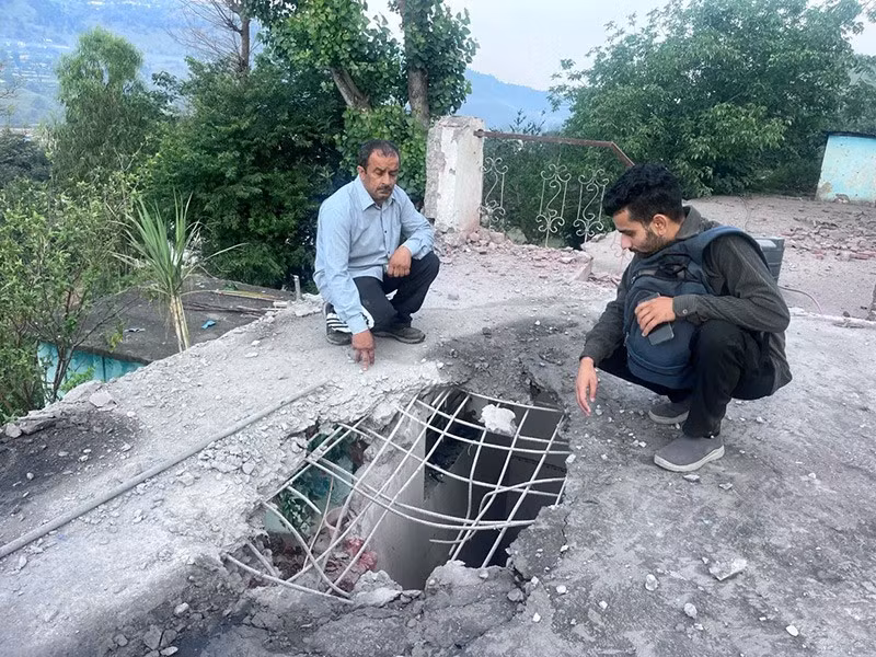 Dân làng Ấn Độ sống gần Đường kiểm soát giữa Ấn Độ và Pakistan xem một lỗ thủng trên mái nhà do đạn pháo của Pakistan gây ra, ở Mendhar. Ảnh: Rahi Kapoor/AP. chum-anh-dap-tra-quan-su-giua-an-do-va-pakistan-070505-010.jpg