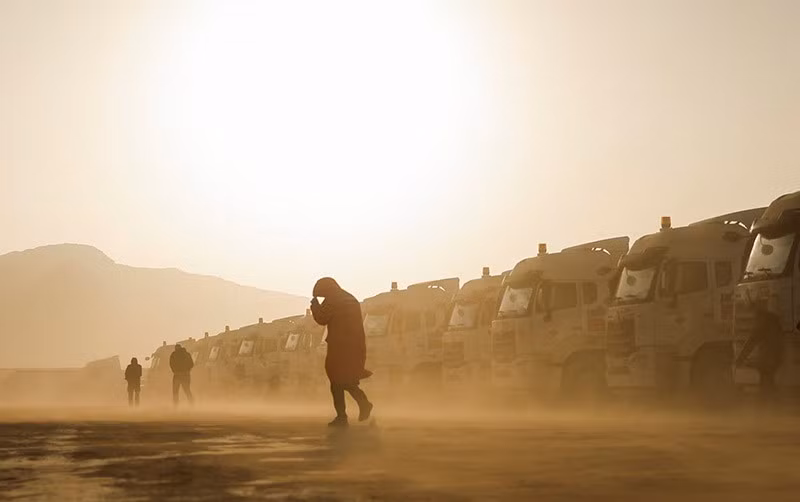 Mọi người đi ngang qua những chiếc xe tải giữa cơn bão cát trước thềm giải đua xe Dakar Rally, ngày 2/1. Ảnh: REUTERS/Maxim Shemetov chum-anh-giai-dua-xe-dakar-rally-2025-016.jpg
