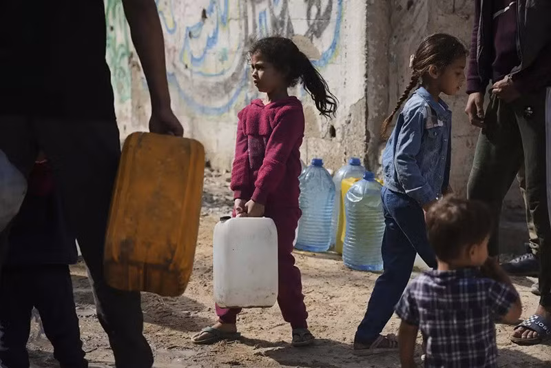 Người dân Palestine lấy nước trong các can nhựa tại một điểm phân phối ở phía tây thành phố Gaza. (Ảnh AP/Jehad Alshrafi) chum-anh-lhq-canh-bao-ke-hoach-phan-phoi-vien-tro-gaza-0505-010.jpg