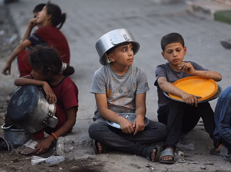 Trẻ em Palestine ngồi chờ nhận đồ ăn từ bếp ăn từ thiện, giữa cuộc khủng hoảng đói nghèo, tại thành phố Gaza, 14/7. Ảnh: Reuters. chum-anh-nan-doi-ngay-cang-nghiem-trong-o-dai-gaza-0705-014.jpg