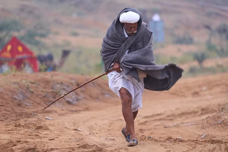 Một người chăn lạc đà, đi về phía lều tạm của mình khi trời mưa nhẹ tại hội chợ thường niên ở Pushkar, bang Rajasthan, Ấn Độ. Ảnh: AP. chum-anh-hoi-cho-lac-da-o-pushkar-an-do-1105-06.jpg
